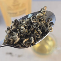 Floral Green Tea leaves on a metal spoon with a blurred background