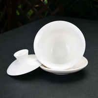 Hand pouring tea from a white gaiwan into a cup
